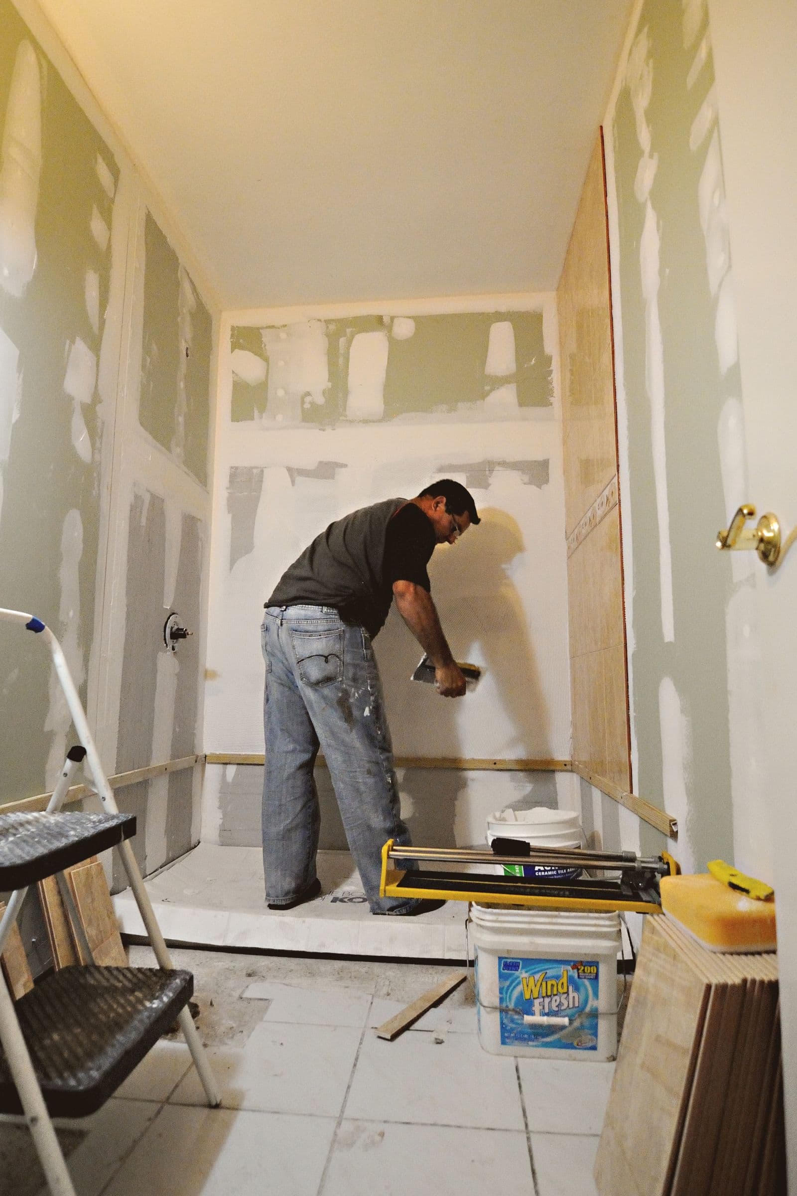 Plasterer applying compound to a wall during a bathroom renovation
